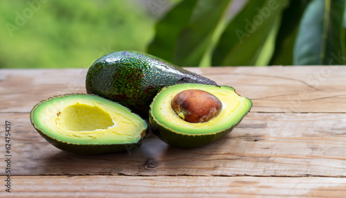 Avocado and avocado pieces on a wooden floor and has a background of nature; Selected focus