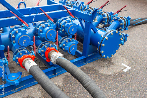Fuel equipment. Hoses are connected to gasoline distribution system. Process of pumping fuel. Gasoline pumping technology for further transportation. Blue fuel equipment on asphalt.