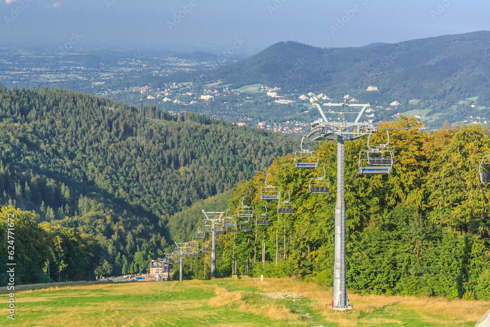 View from the upper station of the chairlift to Mala Czantoria in the Silesian Beskids (Poland) on the Równica hill and the buildings of Ustron on a sunny summer day.