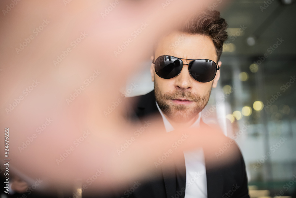 stop gesture, bodyguard in dark sunglasses and black suit looking at camera, showing stop, hotel safety, security management, uniformed guard on duty, professional headshots stop gesture, bodyguard in dark sunglasses and black suit looking at camera, showing stop, hotel safety, security management, uniformed guard on duty, professional headshots