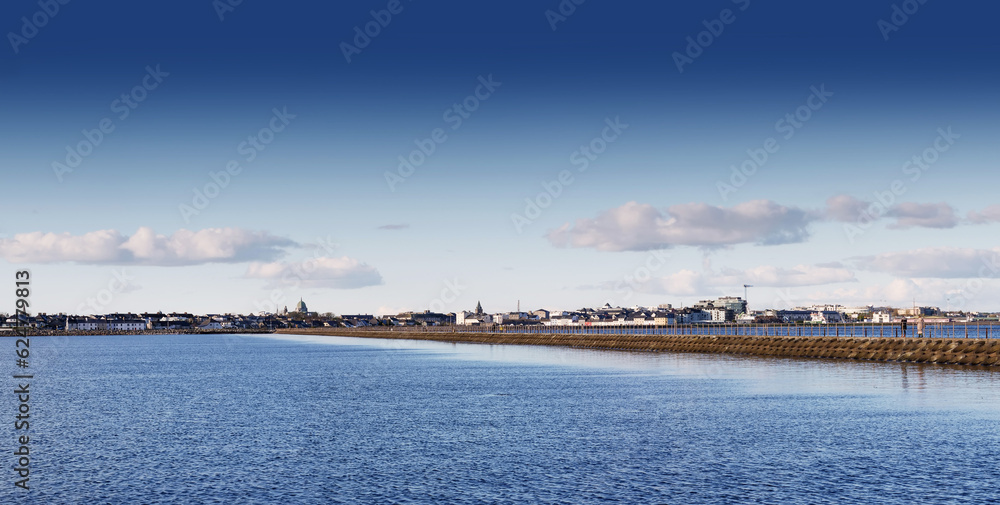 Panorama of Muttun island cause way with blue sky reflecting in the ocean surface. Galway city, Ireland, Irish landscape and architecture. Popular town landmark with view on Salthill promenade
