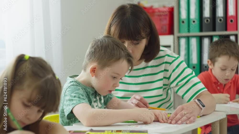 The teacher helps the boy with an individual task. Performing exercises at the desk in elementary school. High quality 4k footage The teacher helps the boy with an individual task. Performing exercises at the desk in elementary school. High quality 4k footage