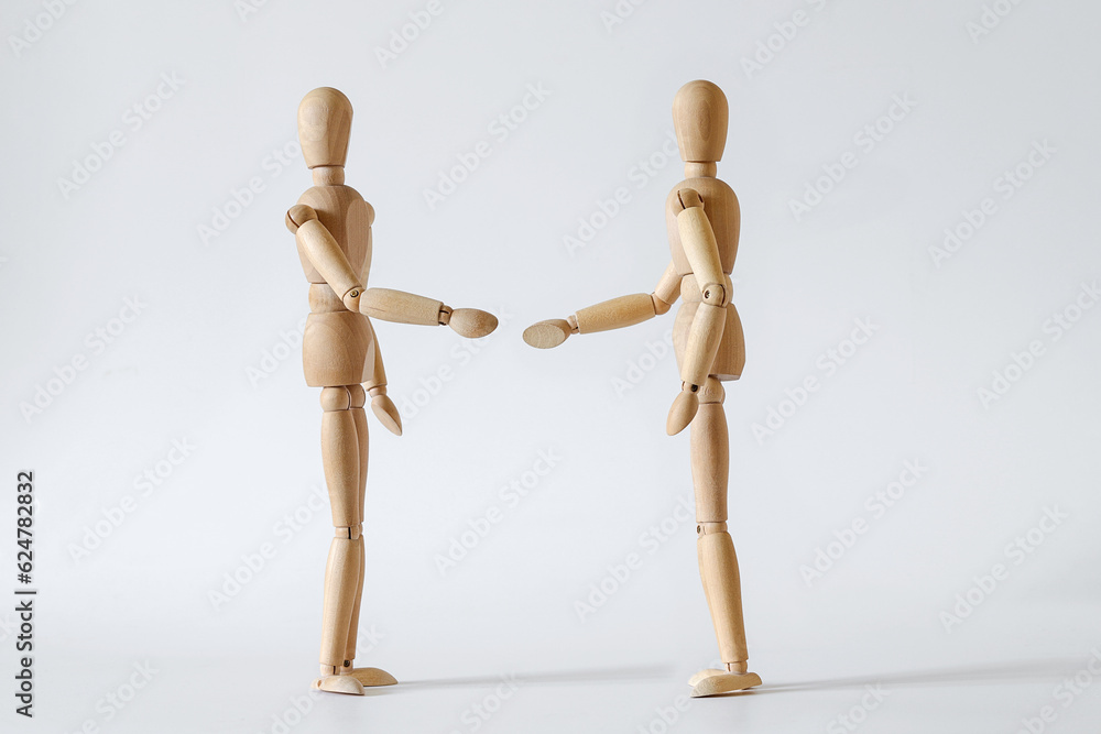 two wooden people extend their hands to each other for a handshake two wooden people extend their hands to each other for a handshake