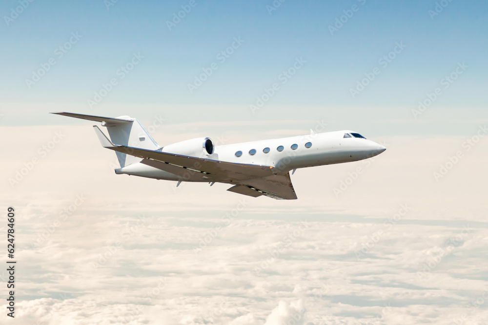 Obraz premium White luxury private jet flying in the air above the clouds