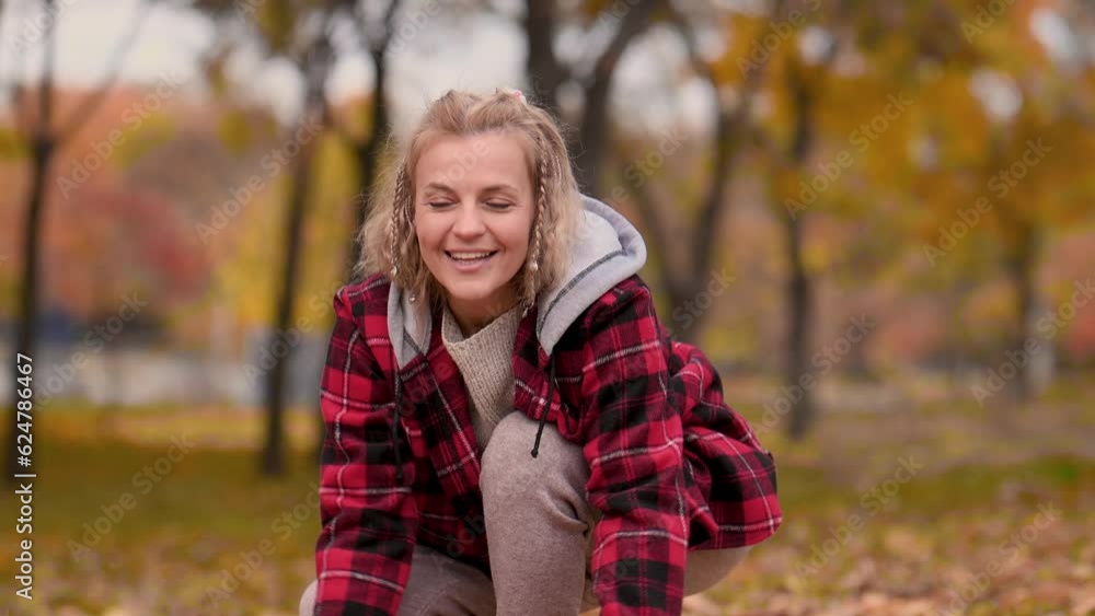 A beautiful mature woman in a red plaid shirt walks in the autumn leaf fall. A middle-aged woman plays with autumn leaves and throws them up. A beautiful mature woman in a red plaid shirt walks in the autumn leaf fall. A middle-aged woman plays with autumn leaves and throws them up.