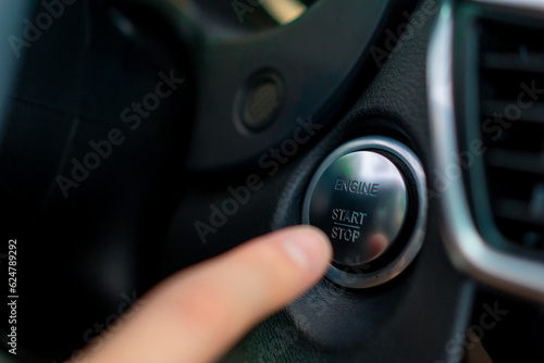 A man presses the start button of his luxury car black car interior © Guys Who Shoot