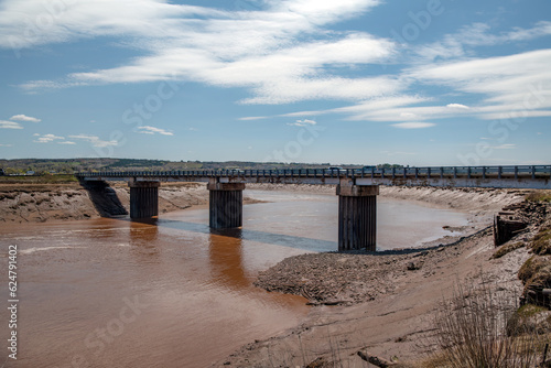 A bridge spanning a very muddy river at low tide.