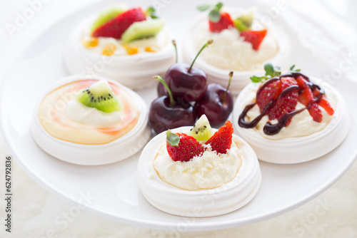 Mini Pavlova desserts topped with fruit on a white plate photo
