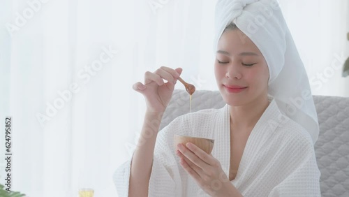 Young woman in bathrobe enjoying honey skin spa. Serene skincare ritual for young woman. Pampering skin spa with honey for young woman in bathrobe.