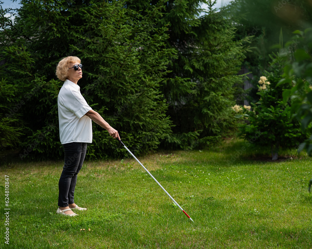 Elderly blind woman walking in the park with a tactile cane. Elderly blind woman walking in the park with a tactile cane.