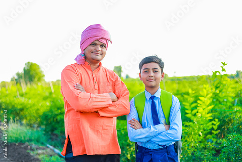 Cute indian farmer child in school uniform with his father at agriculture field