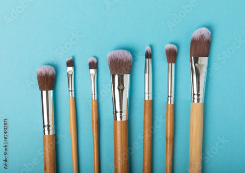 Cosmetic makeup brush on a blue background. Cosmetic product for make-up. Creative and beauty fashion concept. Fashion. Collection of cosmetic makeup brushes, top view, banner.Place for text. 