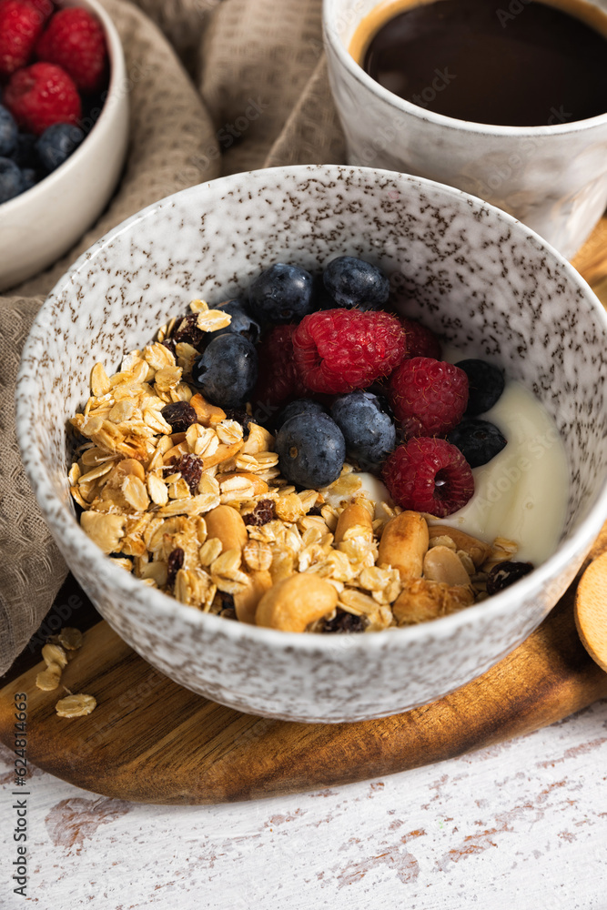 Bowl of homemade oats granola with yogurt and fresh berries on a rustic wooden table. Healthy breakfast with nuts and raisin Bowl of homemade oats granola with yogurt and fresh berries on a rustic wooden table. Healthy breakfast with nuts and raisin
