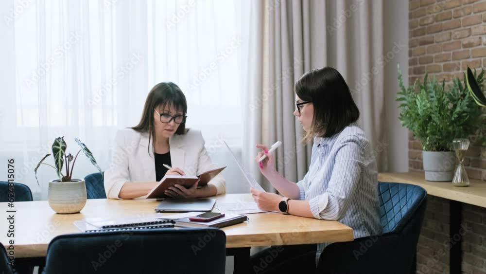 Two serious business women working in office, with papers Two serious business women working in office, with papers