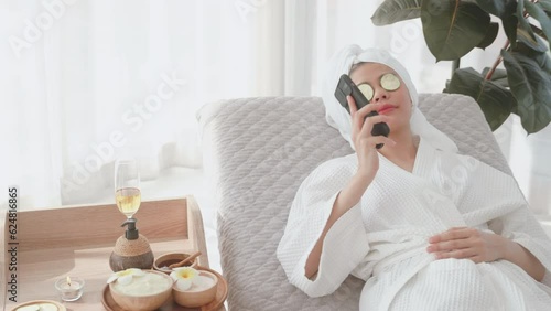 Relaxation concept with young woman in bathrobe enjoying a phone conversation. Young woman in beautiful bathrobe unwinding after shower and taking a phone call.