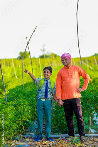 Indian farmer with his son at agriculture field, Father and son are standing in farm, They are happy because of successful sowing and enjoying sunset