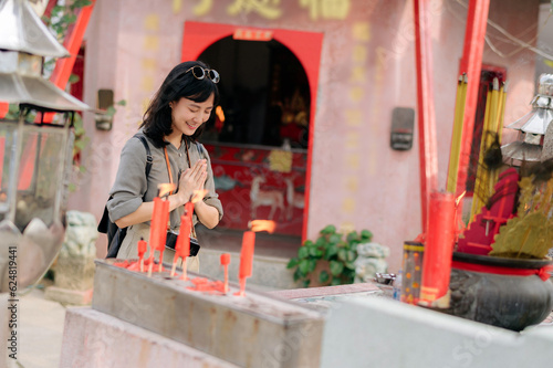 Portrait of asian woman saying prayers and eyes close in front of local Chinese shrine in Bangkok, Thailand