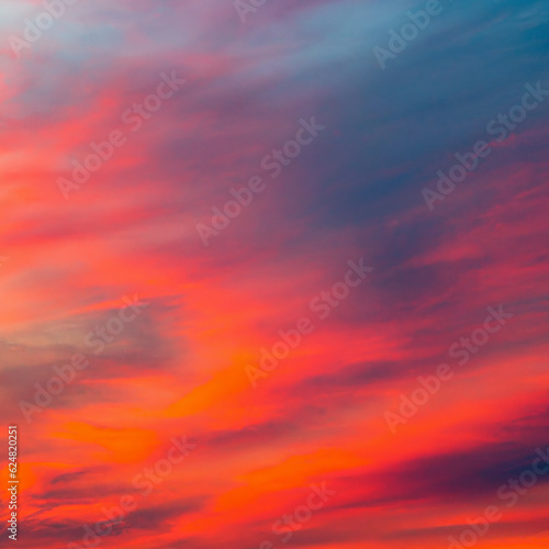 Vibrant orange red colours of sunset sky with clouds. Dramatic sky, light majestic sunset