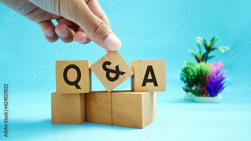 Hands holding wooden block with abbreviations Q and A on wooden block surface with engraved effect of letters Q and A. Close up shot of wooden block Q and A. Selective focus. photo