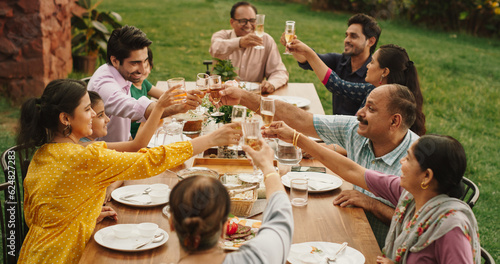 Big Indian Family and Friends Celebrating at Home, Diverse Group of Children, Young Adults and Senior People Gathered at the Table to have Fun Conversation. Clinking Glasses and Making Toast