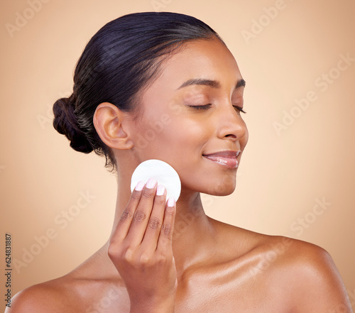 Woman, face and cotton pad, beauty and makeup removal, clean and natural skincare isolate on studio background. Indian female model, cosmetic product and cleaning facial, dermatology and skin glow