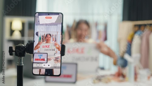 Close-up phone screen recording Asia lady vlogger looking at phone camera live stream  hold whiteboard talk follower introduce her chanel ask audience like subscribe share her chanel at house studio.