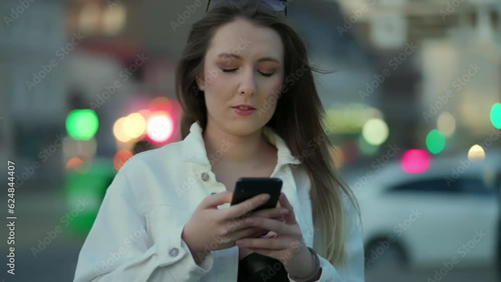 Playful girl chatting on social networks on her phone in the middle of the street in the evening summer, the camera in slowmotion rotates in a circle Playful girl chatting on social networks on her phone in the middle of the street in the evening summer, the camera in slowmotion rotates in a circle