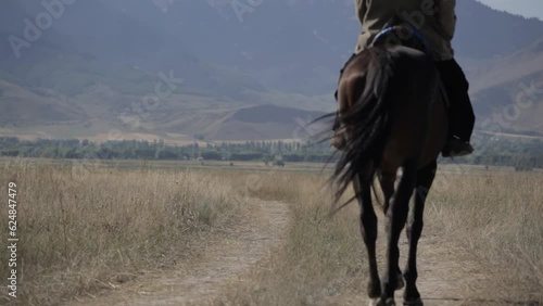 A man in a skullcap on a horse rides across the field