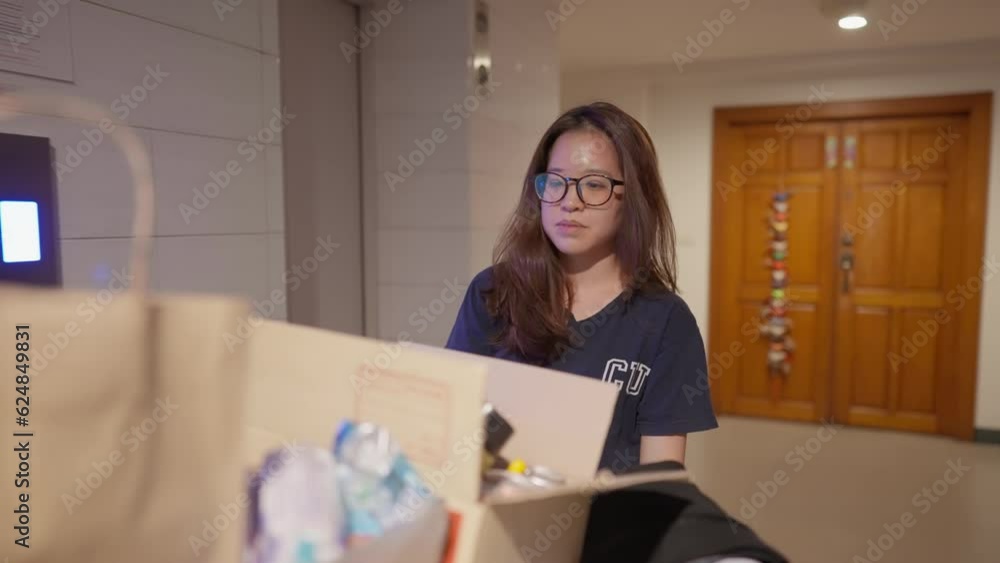 In close-up, a young Asian person pushes a fully packed trolley to the elevator with a visible sense of sadness. their determination , as they navigate life's challenges with quiet strength. In close-up, a young Asian person pushes a fully packed trolley to the elevator with a visible sense of sadness. their determination , as they navigate life's challenges with quiet strength.