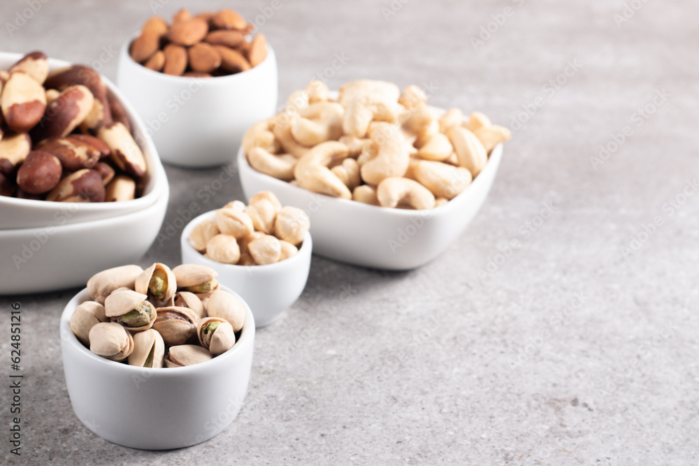 Large assortment of nuts in different bowls on stone table. Large assortment of nuts in different bowls on stone table.
