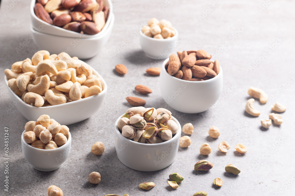 Large assortment of nuts in different bowls on stone table. Large assortment of nuts in different bowls on stone table.