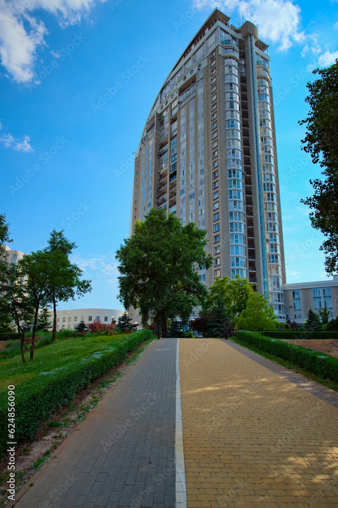 Low-angle view of modern high rise residential building. Blue sky with white clouds in the background. Modern architecture from glass and steel. Concept of real estate in Kyiv, Obolon neighborhood Low-angle view of modern high rise residential building. Blue sky with white clouds in the background. Modern architecture from glass and steel. Concept of real estate in Kyiv, Obolon neighborhood