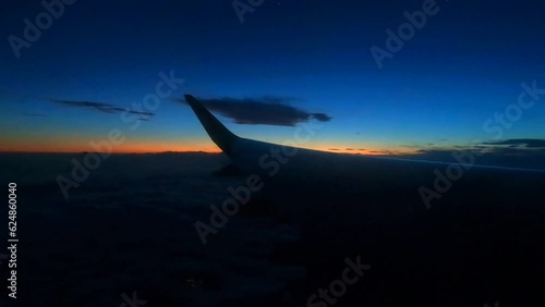 a wing of an airplane with a flashing lantern on the background of sunset in the sky