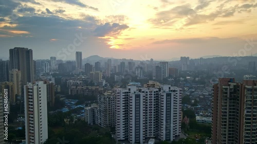 Aerial 4k cityview of Indian suburban Mumbai during a beautiful sunset over cityscape of buildings, hills and lake. Mumbai drone at sunset with rooftop view. Third world country