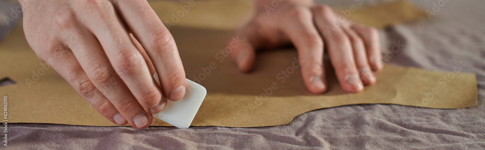 Cropped view of artisan holding chalk while marking sewing pattern and fabric and working in print studio, multitasking business owner managing multiple project, banner Cropped view of artisan holding chalk while marking sewing pattern and fabric and working in print studio, multitasking business owner managing multiple project, banner