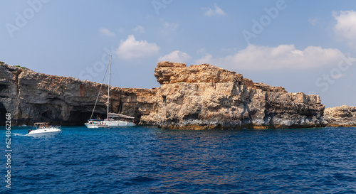 Motor boats with tourists sails coastal caves at Blue Lagoon of Comino