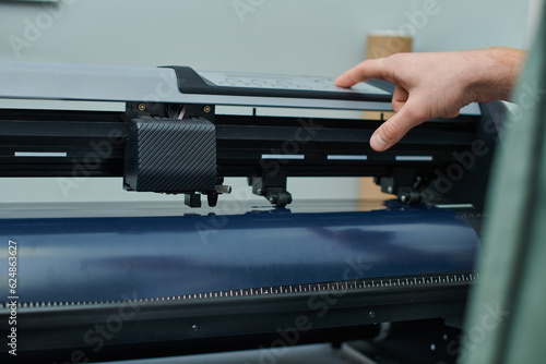 Obraz na płótnie Cropped view of young craftsman using screen printing machine during process in