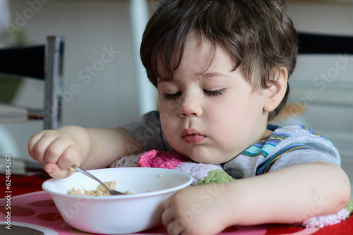 cute young boy eating healthy oatmeal for breakfast