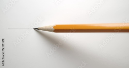 Drawing a straight line across paper with a yellow pencil. photo