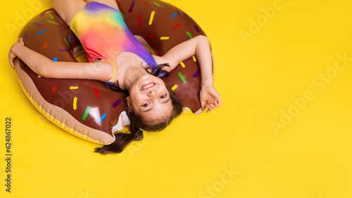 Bilde på lerret upside down girl in one-piece rainbow colored swimsuit swims in inflatable ring