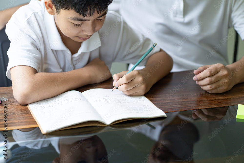 Asian father helps son to do her homework for the school..child study together homeschooling concept getting homework help from father Asian father helps son to do her homework for the school..child study together homeschooling concept getting homework help from father