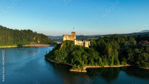 Poland. Medieval castle in Niedzica in sunset light. Artificial Czorsztyn lake on Dunajec river, damn and hydro power station. Aerial approaching video