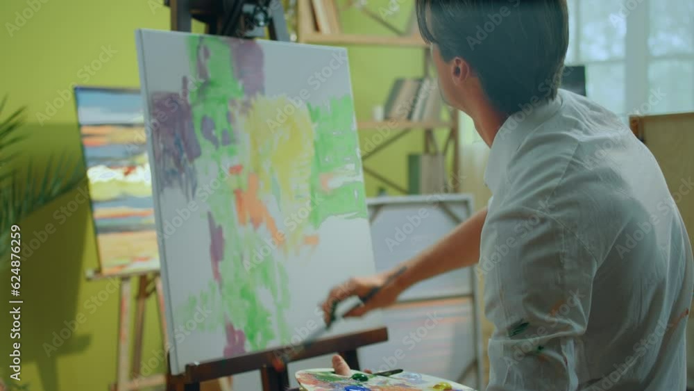 In front of the camera closeup the artist man mixed some oil colour from the palette and add on the picture at the art studio In front of the camera closeup the artist man mixed some oil colour from the palette and add on the picture at the art studio