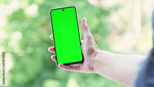 Woman holding phone with chroma key vertically (green screen) photo