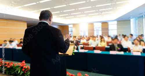 Business man making a speech in front of big audience at a conference hall photo