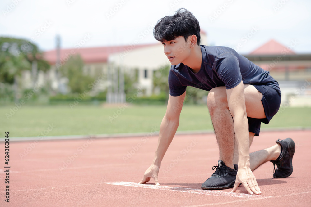 An asian man ready to run at start point with concentration emotion at sport field background.