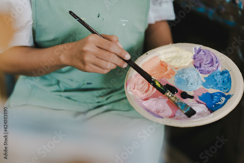 Close-up of female artist painting on canvas with brush Young painter working on the floor of her art studio creative young woman painting with oil paints creative concept