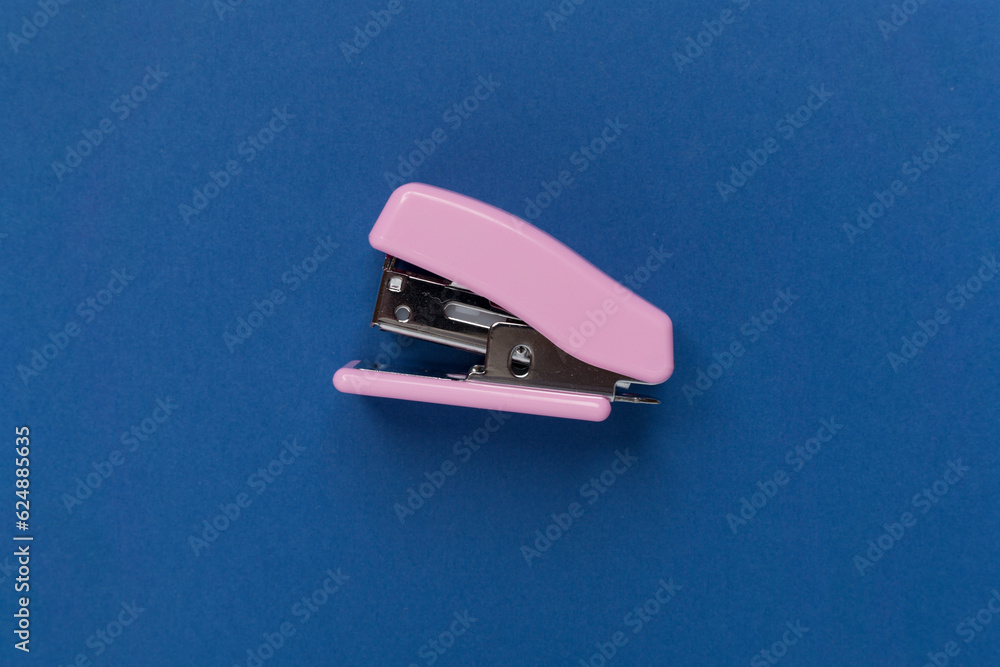 Pink stapler on color backgroung, top view
