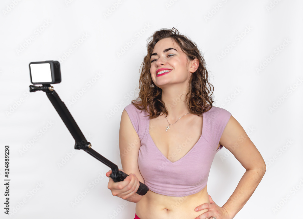 Cute woman laughing while taking selfie. A woman poses in the studio, holding a selfie stick. Cute woman laughing while taking selfie. A woman poses in the studio, holding a selfie stick.