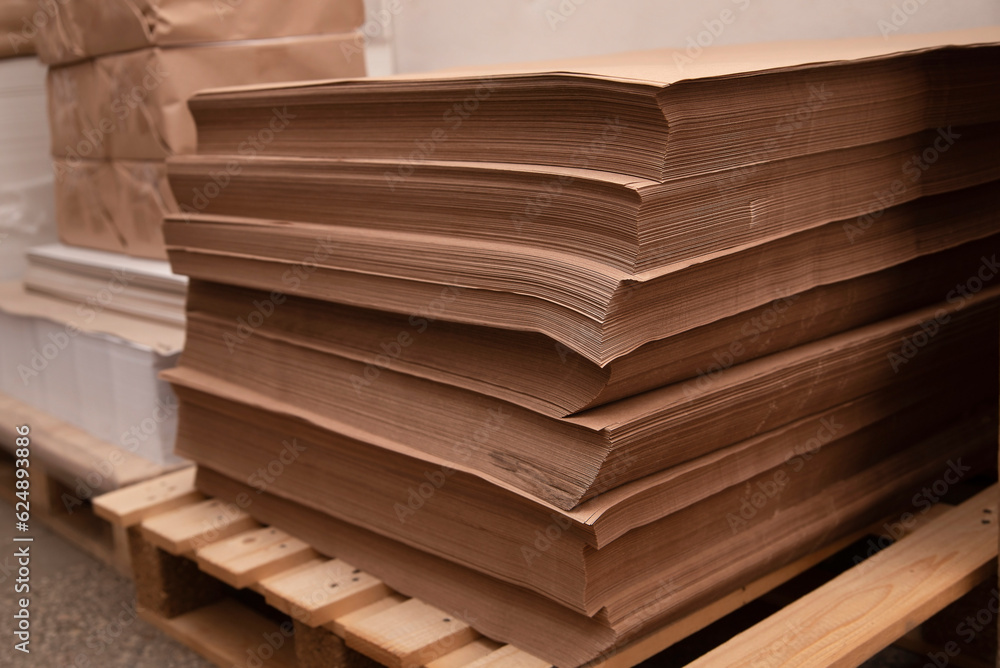 Kraft paper sheets on wooden pallets have just been brought to the printing house and are being acclimatized, kraft paper sheets are damaged during transportation